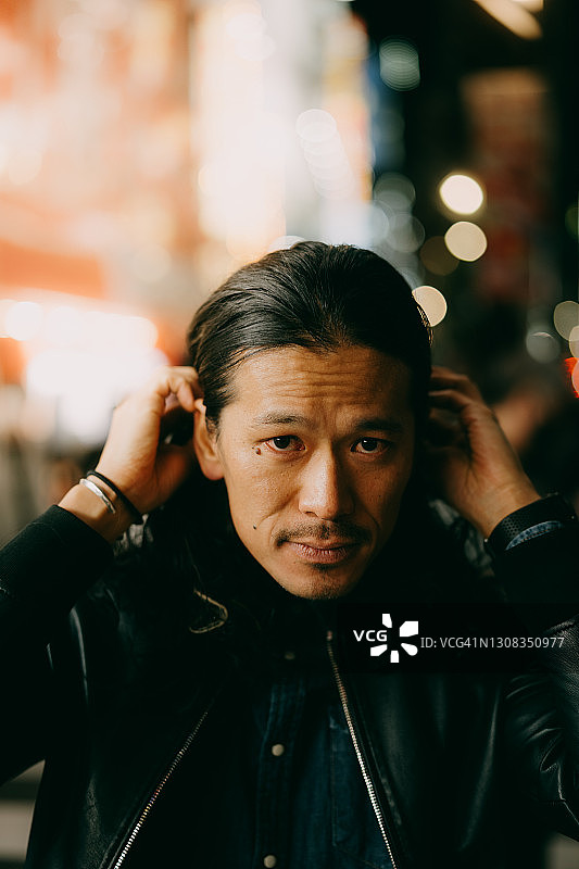 一名日本男子在东京夜晚的城市街道上看着摄像机图片素材