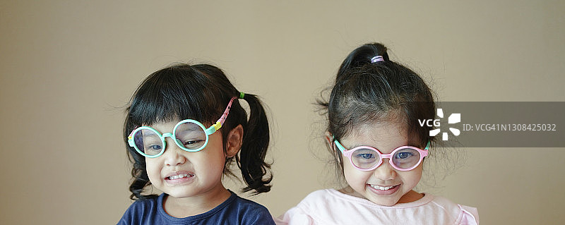 萌萌的小学前班小女孩戴着眼镜看相机的大头照，孩子视力矫正治疗的概念图片素材