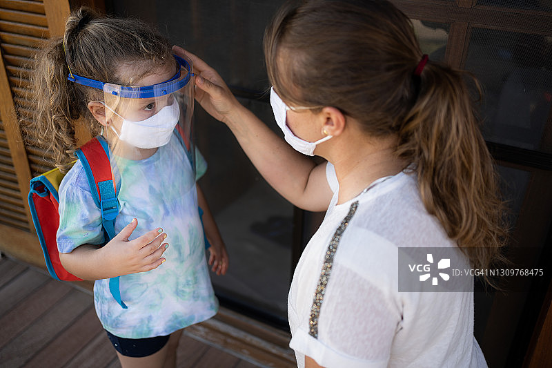 2019冠状病毒病期间母女佩戴防护口罩准备上学。新常态图片素材
