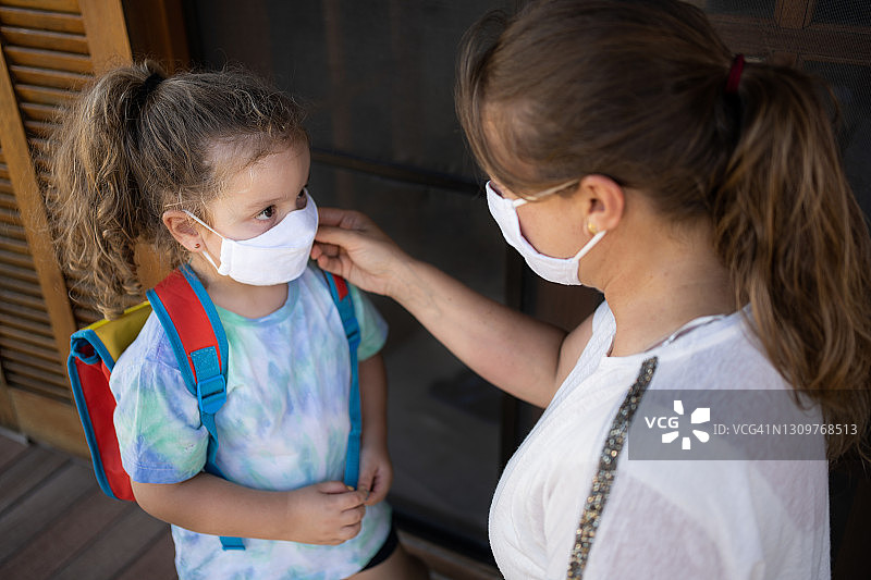 2019冠状病毒病期间母女佩戴防护口罩准备上学。新常态图片素材