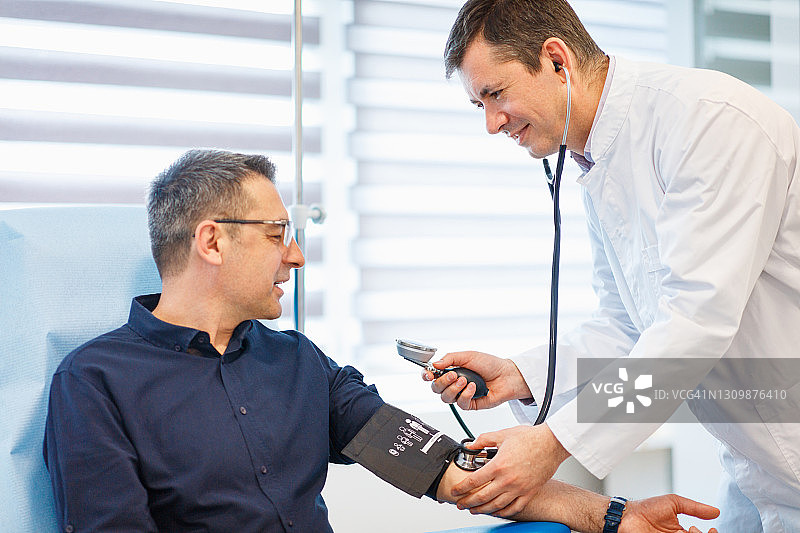 医生测量人的血压和脉搏在积极的气氛图片素材