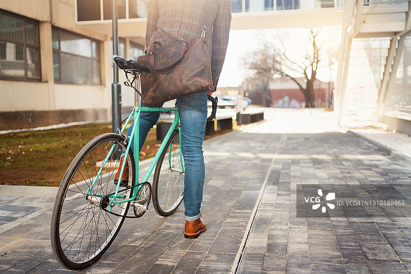 一个面目全非的时尚商人背着皮包，骑自行车上班图片素材