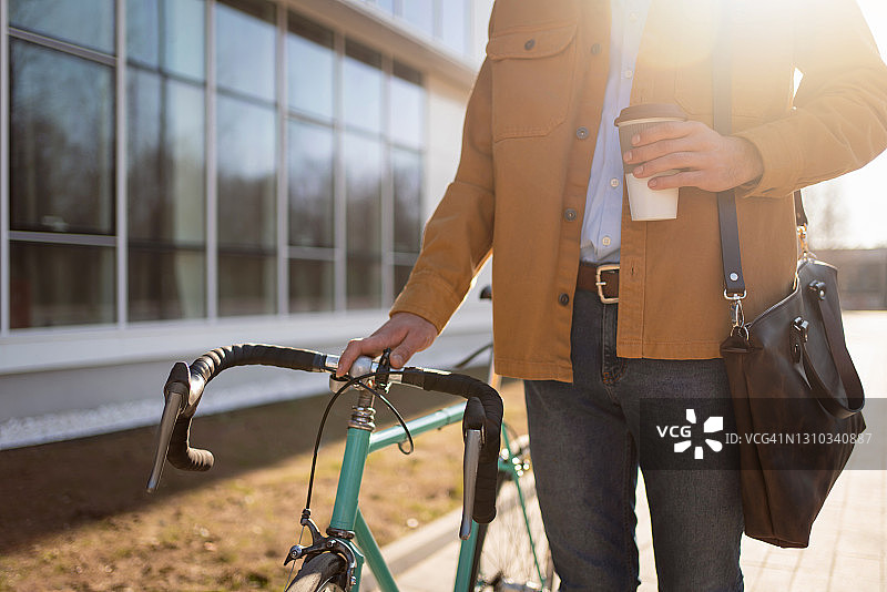 一个不认识的人与他的自行车拿着一杯咖啡走的特写图片素材