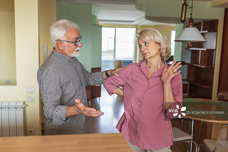 一位老人和他的妻子正在家里进行一场严肃的讨论。图片素材