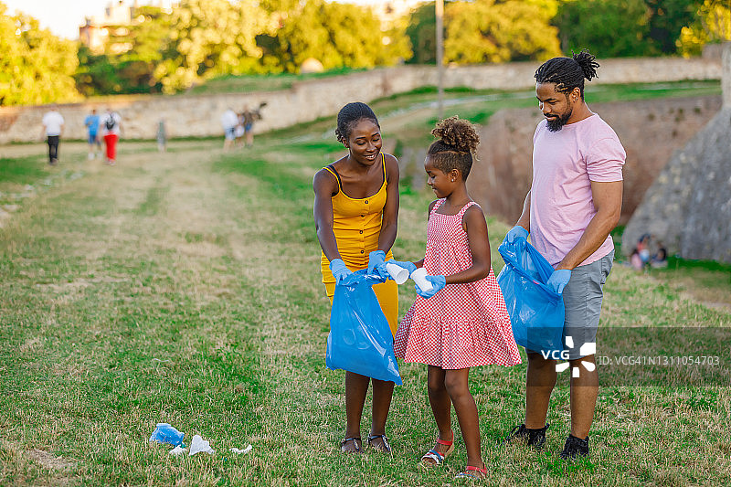 快乐的非洲家庭在公园里捡垃圾。图片素材