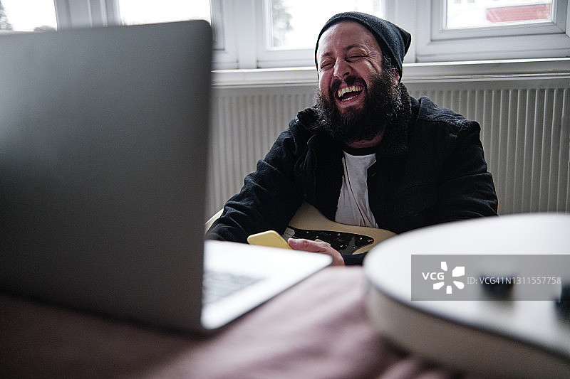 一个拿着笔记本电脑在家笑的成熟男人图片素材
