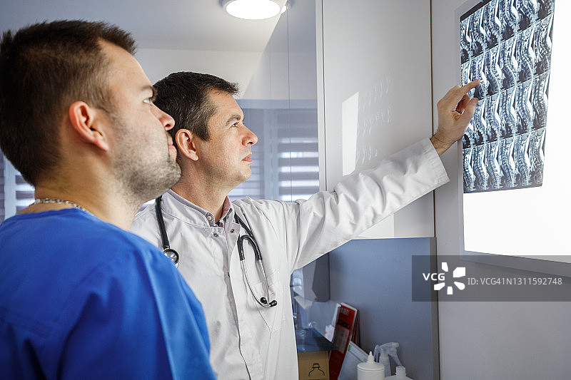 放射科医生指着MRI扫描上的图像给脊柱外科医生图片素材