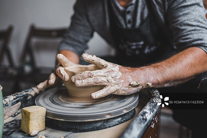 在陶器作坊里，男性的双手正在制作陶罐图片素材