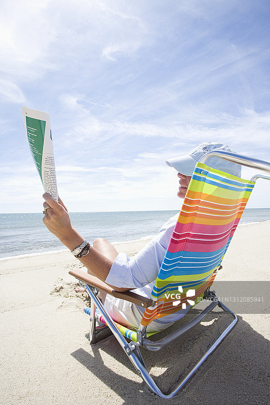 美国，马萨诸塞州，南塔开特，女人在海滩上阅读杂志图片素材
