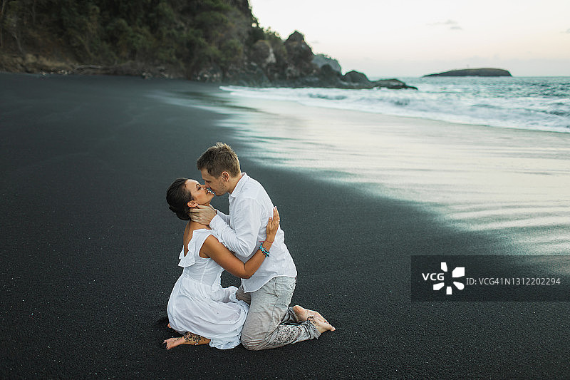 感性的夫妇接吻与激情和欲望在海滩上的海水与波浪飞溅。年轻的恋人图片素材