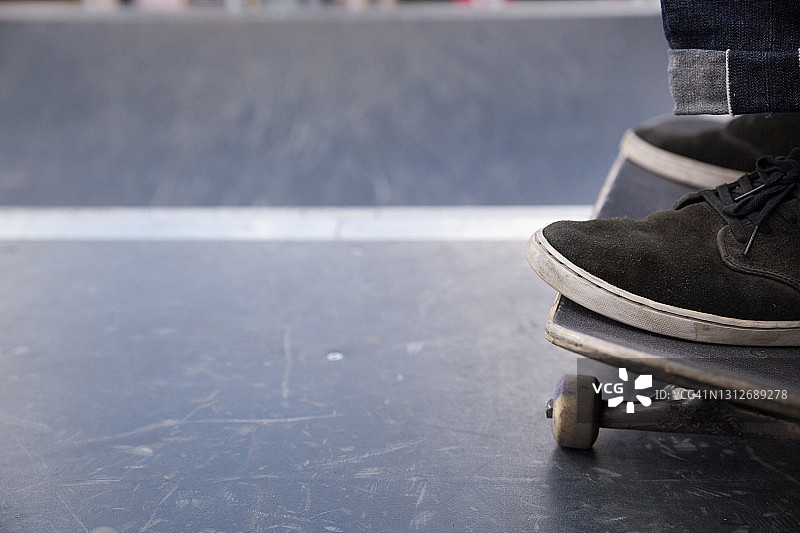穿着黑色运动鞋的男人的脚站在街上溜冰。图片素材