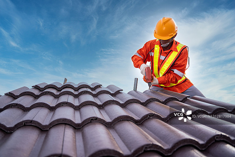 在施工现场对建筑物的屋顶结构进行施工，屋面施工人员使用空气或气动钉枪，并在新屋顶上安装瓦。图片素材