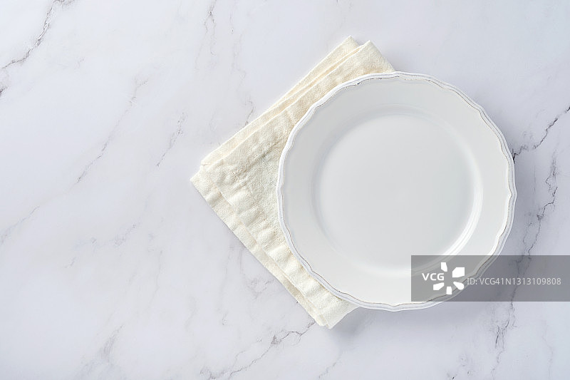 清空白色的盘子和毛巾在白色的大理石桌上为你的食谱或菜单。前视图。模拟。图片素材