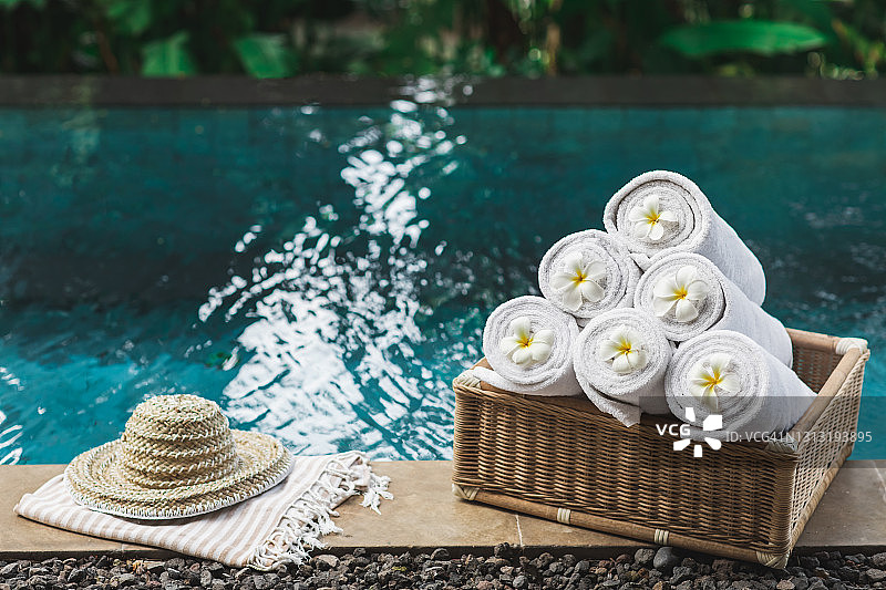 泳池边的柳条箱、草帽、白色卷巾，装饰热带花卉图片素材