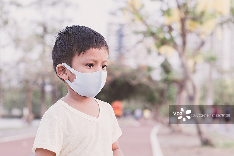 亚洲小男孩戴着口罩在公园里保护pm2.5和冠状病毒。图片素材