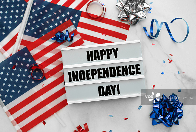 美国国旗，五彩纸屑，白色背景上印有“独立日快乐”字样的灯箱。7月4日，独立日。图片素材