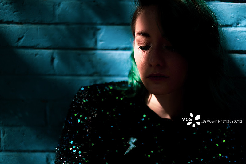 一个有着绿色头发的年轻女子俯视着墨西哥城，部分被阴影遮住了图片素材