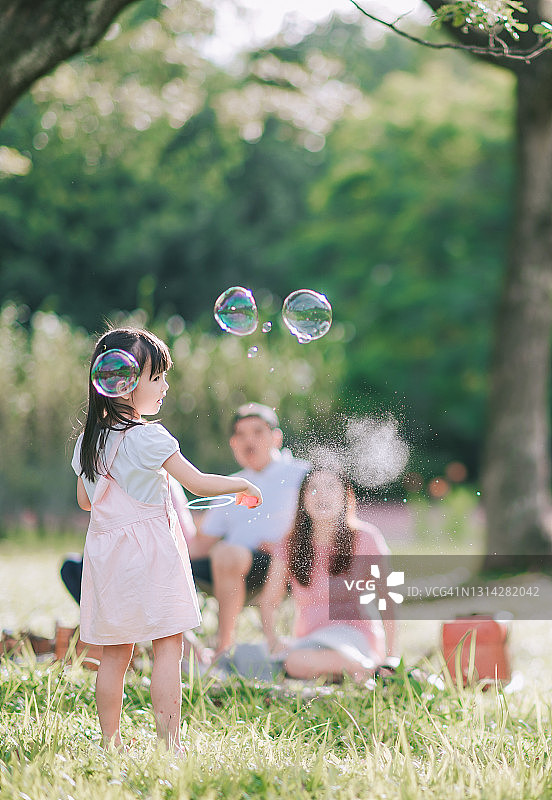 亚洲华人的女儿女孩的孩子拿着泡泡棒在早上的公园背光阳光下图片素材