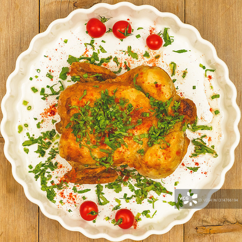 烤鸡与香草，西红柿在白色盘子上木制桌子背景俯视图图片素材