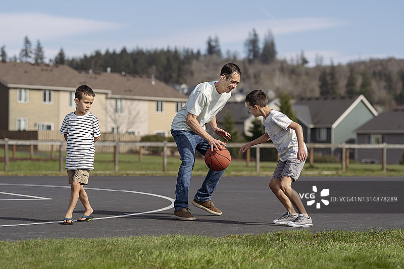 混血爸爸在公园打篮球是小学年龄的儿子图片素材