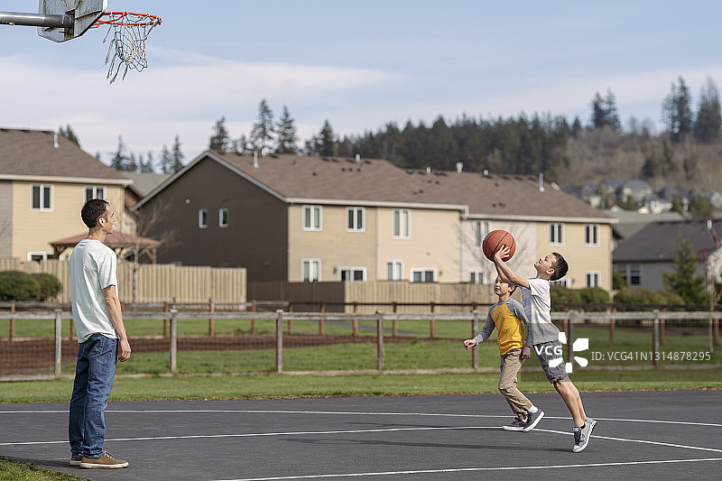 小学男孩和他们的爸爸在公园里打篮球图片素材