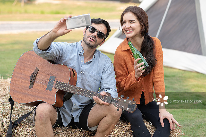 一对年轻的情侣喜欢在露营地弹吉他图片素材