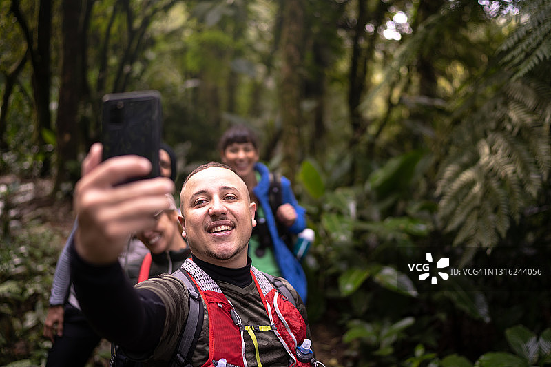 一群人在森林徒步旅行时用智能手机拍摄图片素材