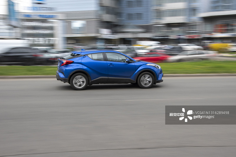 蓝色丰田C-HR汽车在街上行驶。图片素材