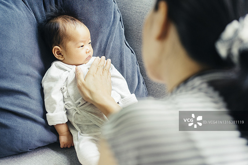亚洲单身母亲在家里安慰刚出生的女儿喂奶后打嗝图片素材