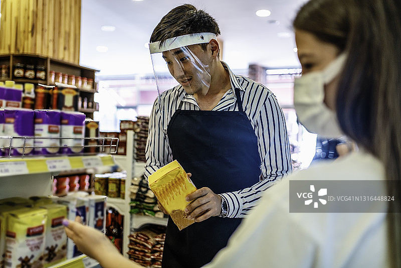 收银员或超市工作人员戴医用防护口罩和面罩在超市工作。covid-19疫情蔓延图片素材