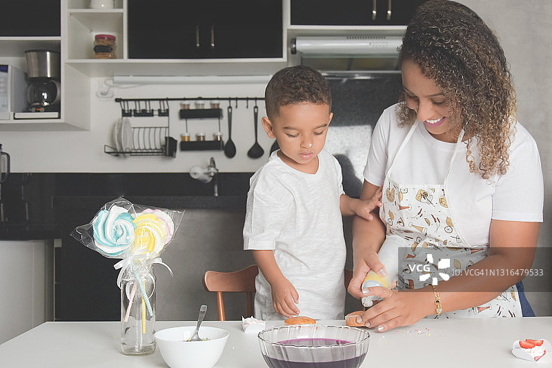 母亲和儿子在厨房玩纸杯蛋糕和糖衣图片素材