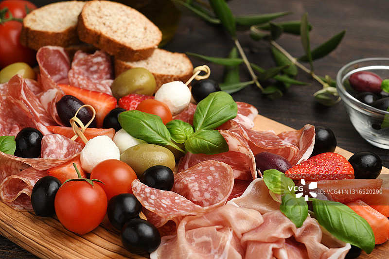 意大利香肠，意大利熏火腿，绿橄榄和黑橄榄，开胃菜，马苏里拉奶酪球，樱桃番茄和草莓。图片素材