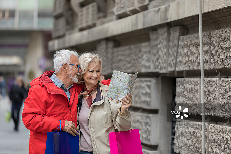 高级游客和他的妻子拿着旅游地图在市区散步。图片素材