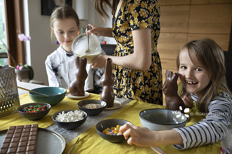 孩子和十几岁的姐妹们坐在餐桌前，制作复活节巧克力点心图片素材