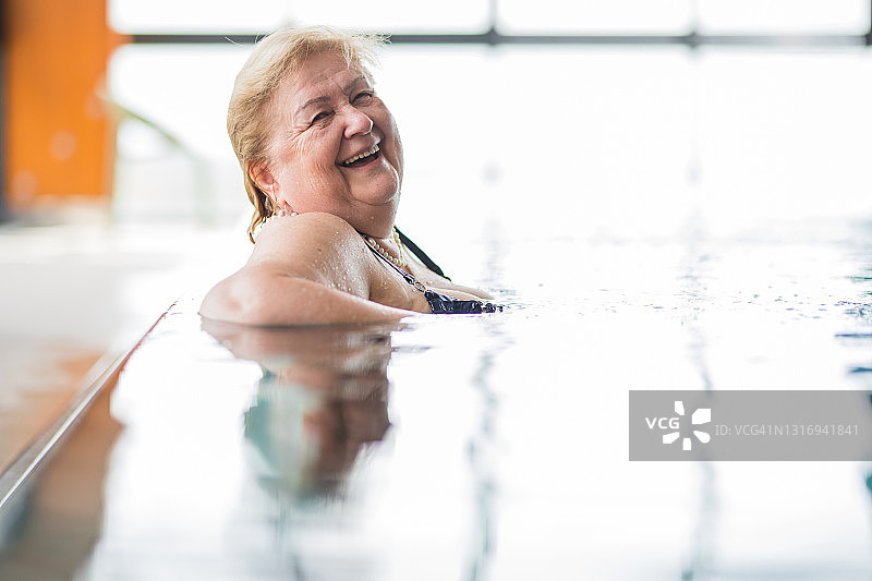快乐的老年妇女在游泳池微笑图片素材
