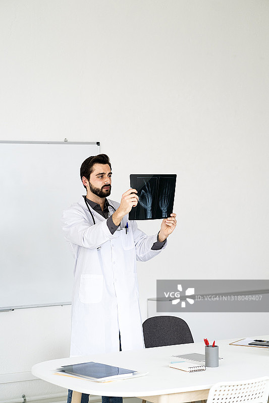 男医生站在医院办公桌前分析x光报告图片素材