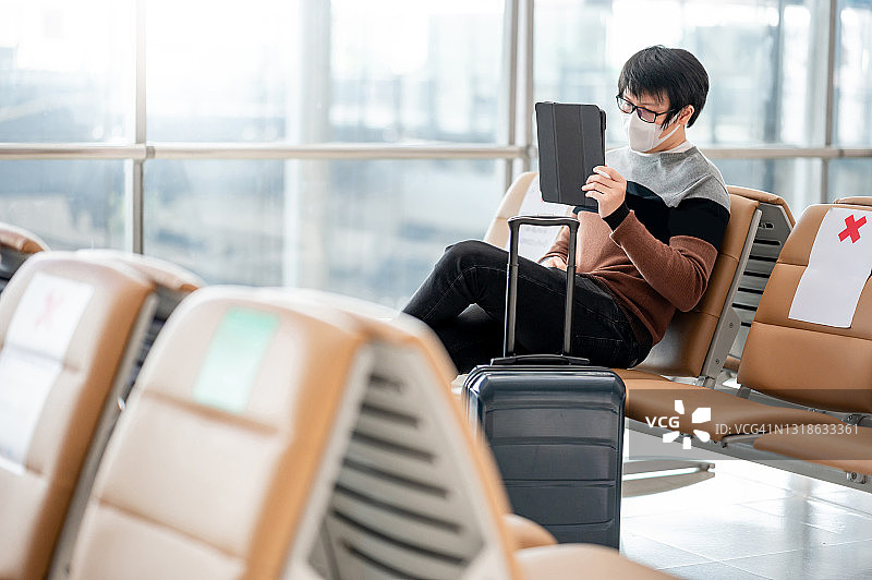 亚洲男子游客在机场航站楼使用平板电脑图片素材