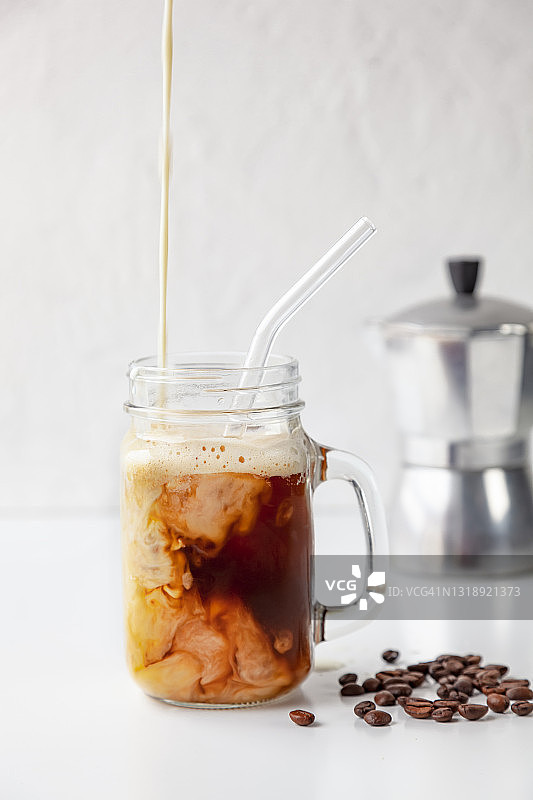 特写“咖啡”(蛋白质和咖啡)在Mason Jar与可重复使用的玻璃饮用吸管在白色的背景图片素材