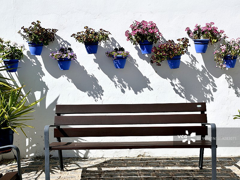 坐在典型的安达卢西亚街道上的长椅(白色立面上有花)图片素材