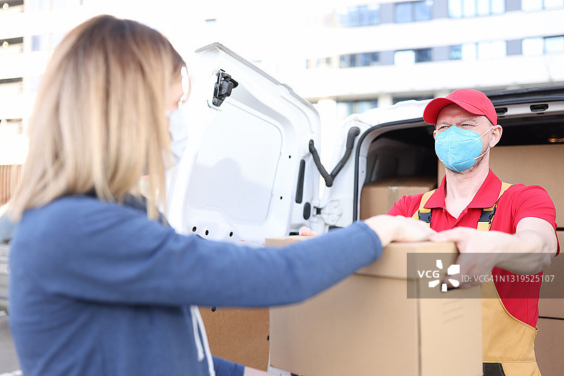 男快递员戴着医用防护口罩给女快递员纸盒图片素材