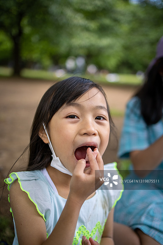 小女孩在公园里吃零食图片素材