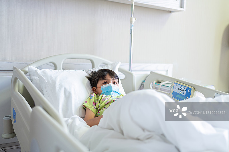 带防护口罩的患儿躺在医院病床上图片素材