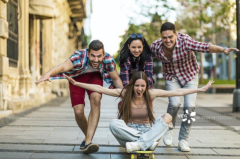 一群快乐的学生在城市街道上玩滑板时玩得很开心图片素材
