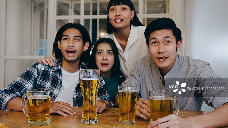 一群年轻的亚洲游客朋友在体育电视上看足球，喝啤酒，在考山路的夜总会聚会。图片素材