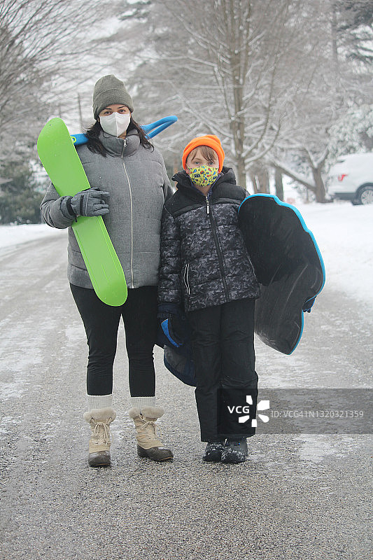 一个母亲和她的小男孩在一个冬天搬运雪橇的肖像图片素材