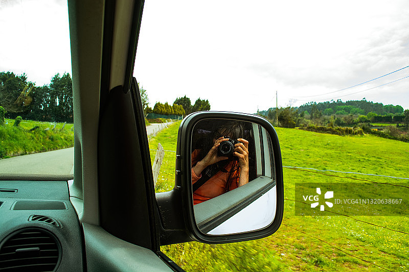 一个女人拿着相机看着车里的镜子图片素材