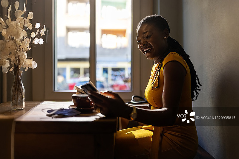 一个在咖啡店里用手机发短信的快乐女人图片素材