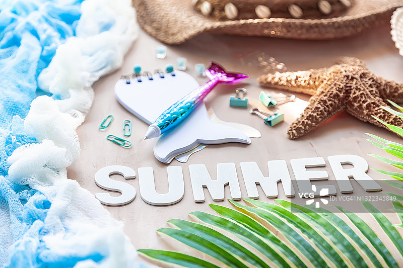 题词夏天在白色木材字母与棕榈树叶，草帽，海星，空白便条本和办公用品的背景。夏季海滩旅游概念。图片素材