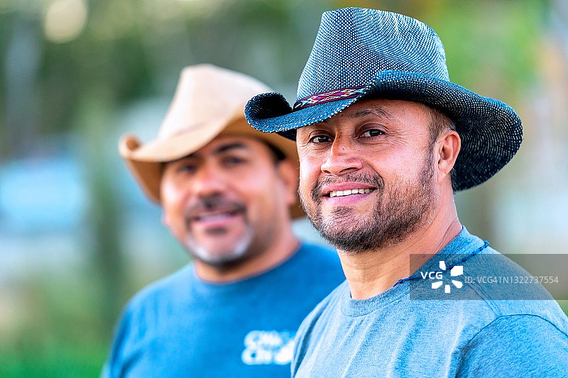 两个西班牙成熟的农业男性工人戴着牛仔帽看着镜头微笑着图片素材