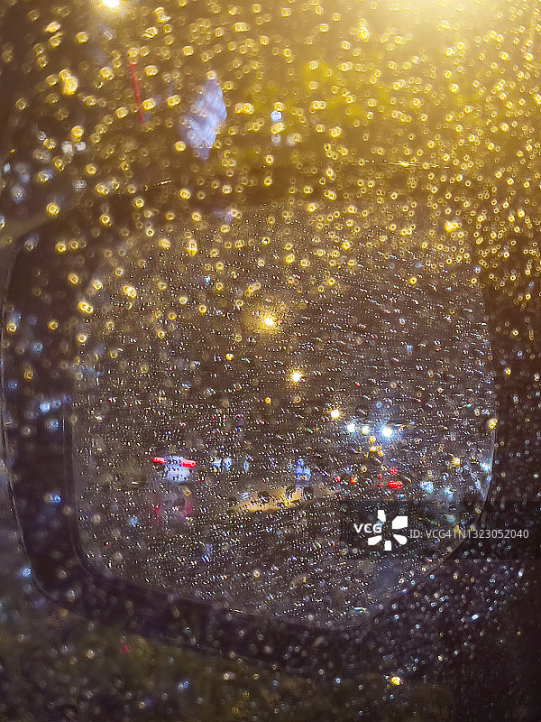 街灯下的汽车后视镜上布满了雨滴图片素材